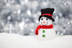 a small snowman figurine wearing a scarf and hat, sitting in the snow