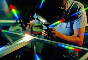 a welder with ahis face shield down welds, setting off a spectrum of color