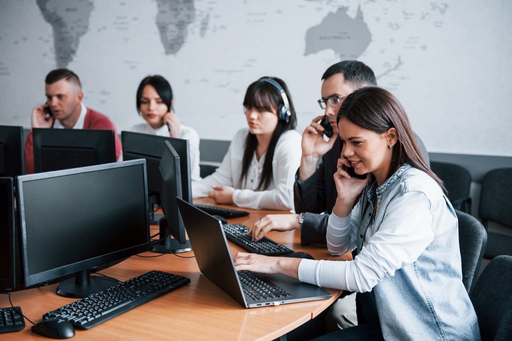 employees working in the office, sitting at a desk, using phones and computers