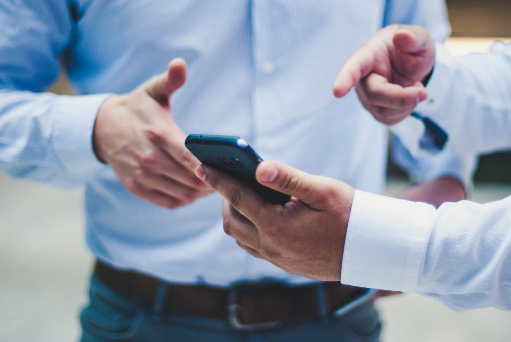 2 coworkers discuss something they see on the cell phone