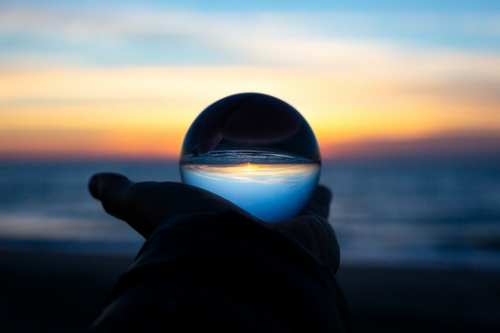 a hand holding a crystal ball at dawn
