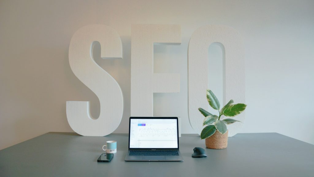 desk with laptop, phone, coffee, and large SEO letters