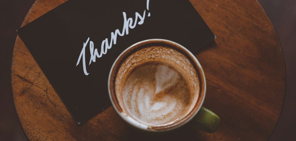 a coffee cup and a thank you note